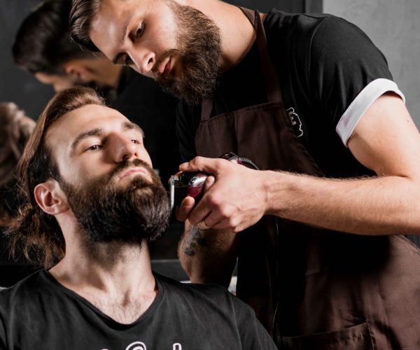 hairdresser-trimming-man-s-beard-with-electric-razor_11zon